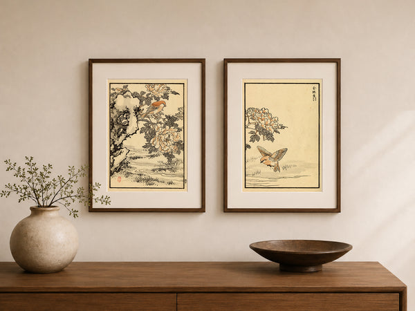 Two framed Japanese-style art prints hang on a beige wall above a wooden console table. The left print shows a bird perched on a flowering tree, and the right print shows a butterfly near flowers.