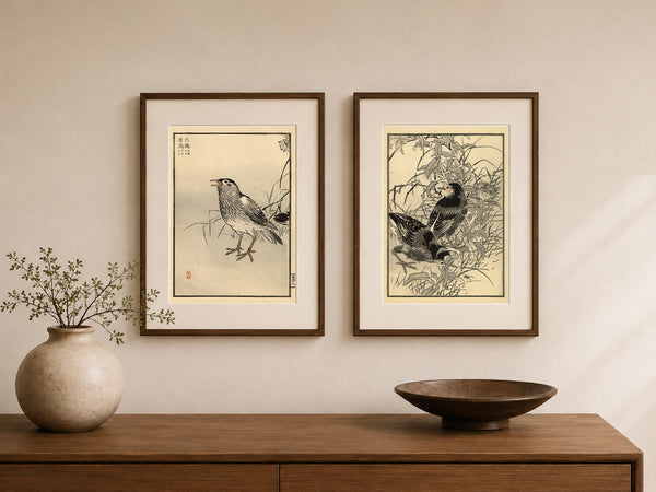 Two framed Japanese-style bird art prints hang on a beige wall above a wooden console table, with a ceramic vase and a bowl as decor.