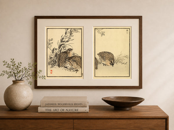 A framed pair of Japanese woodblock prints depicting quail birds, displayed on a beige wall above a wooden console table with a vase, books, and a bowl.